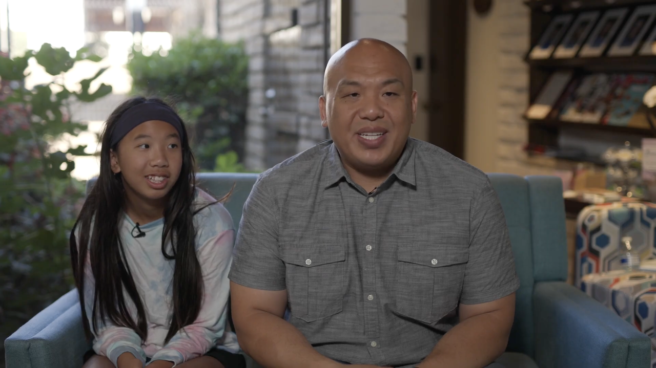 Asian father and daughter sitting and looking into camera in the lobby of Temple City Dental Care.