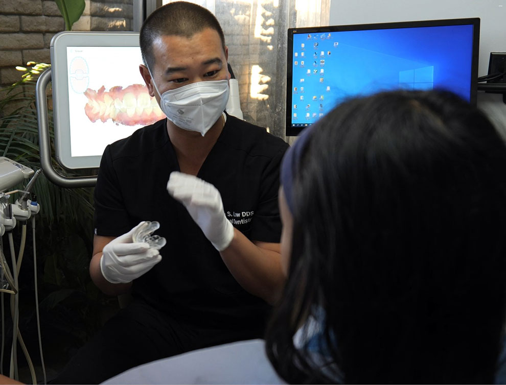 Dr. Kyle Low talking with patient as she sits in dental chair.