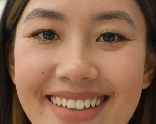 Close up face of a happy Asian woman smiling looking at camera.