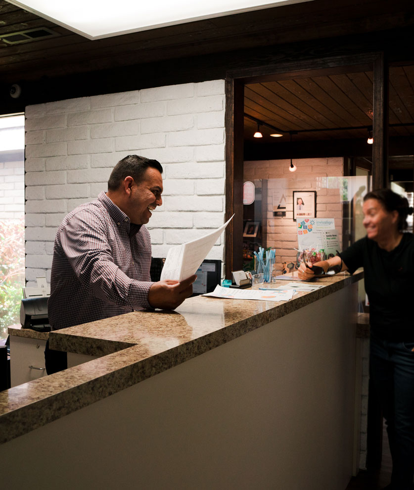 Ramone smiling with a patient at the front desk.