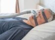 Man using a CPAP machine while he sleeps to treat sleep apnea