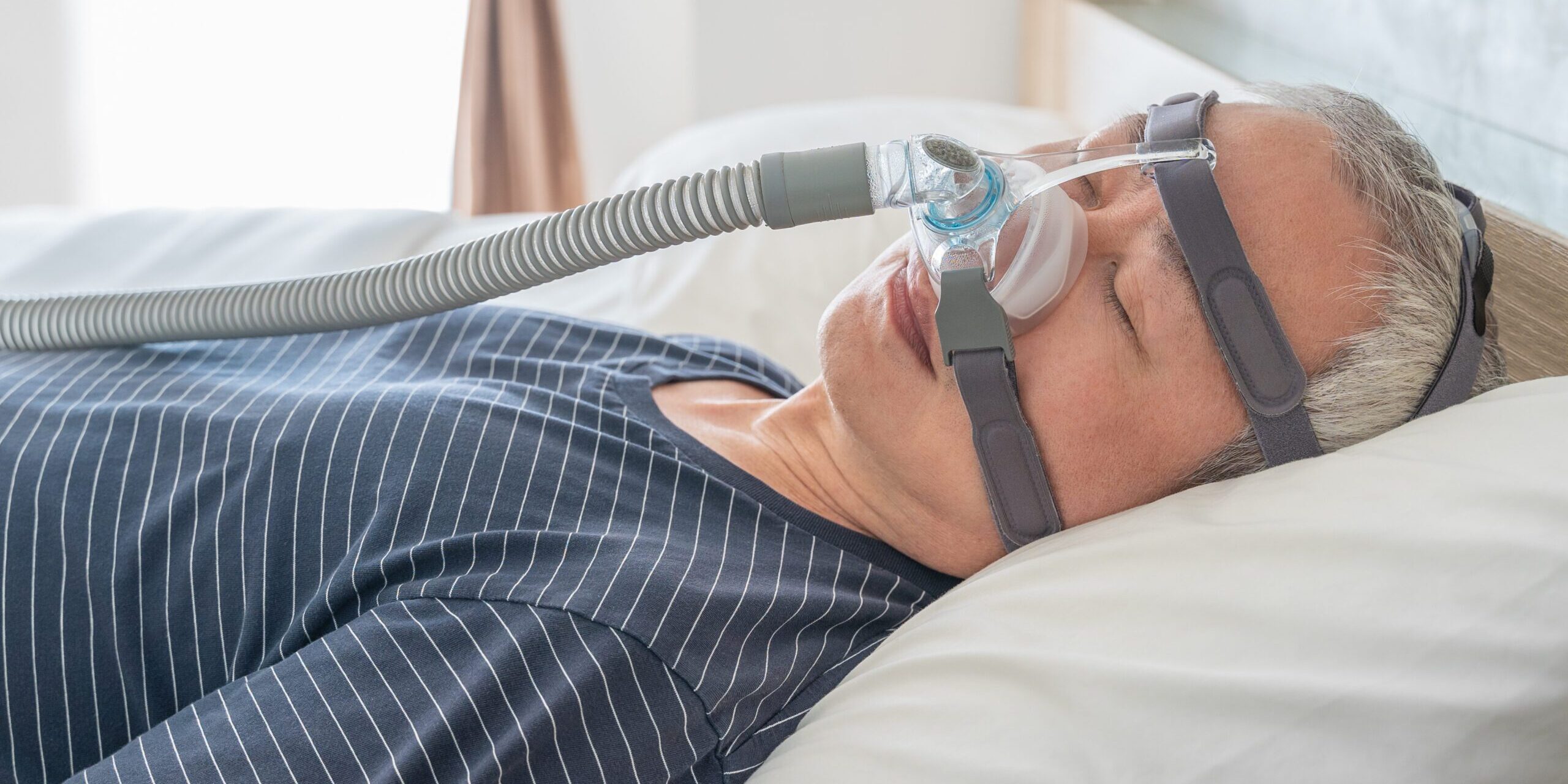 Man using a CPAP machine while he sleeps to treat sleep apnea