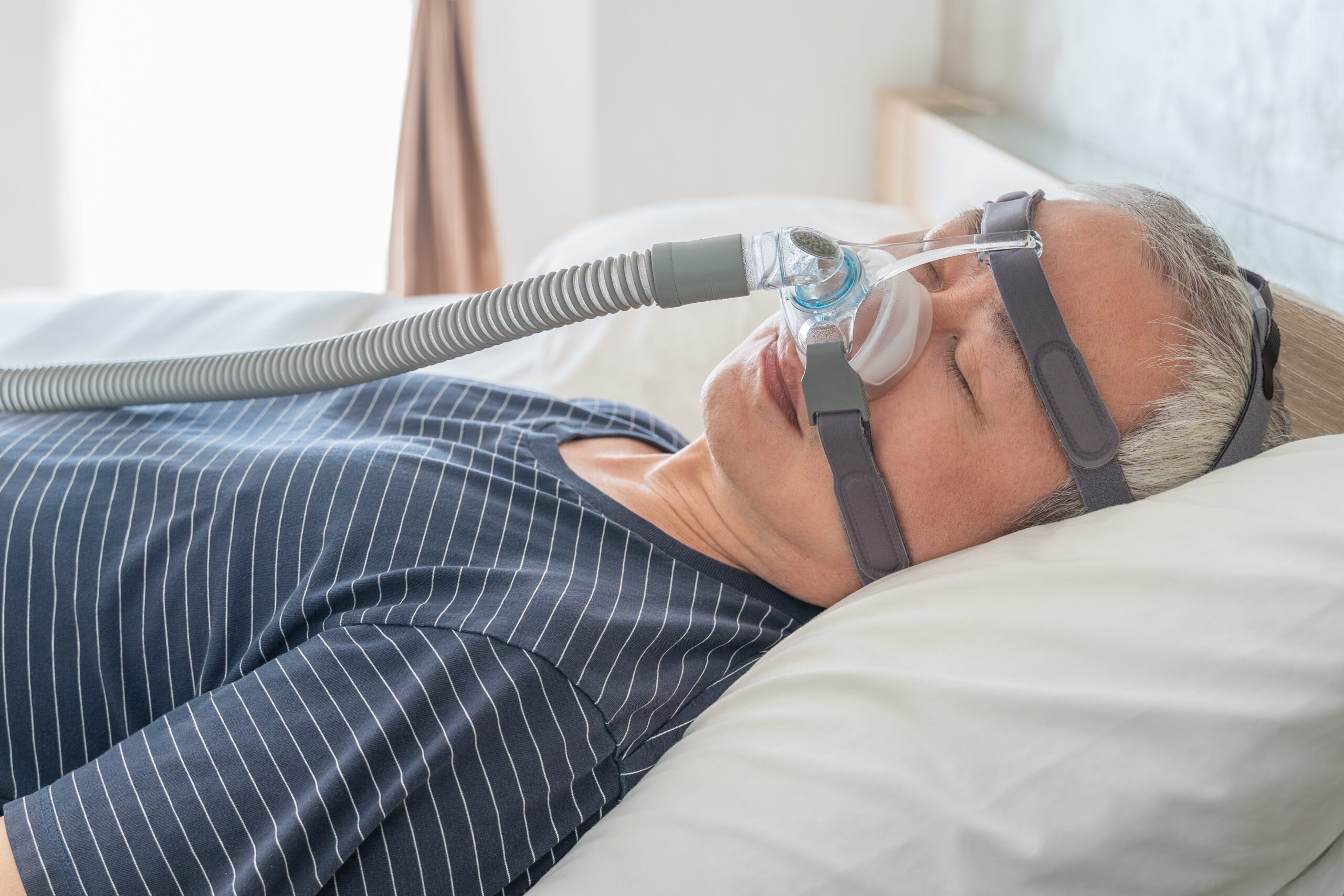 Man using a CPAP machine while he sleeps to treat sleep apnea