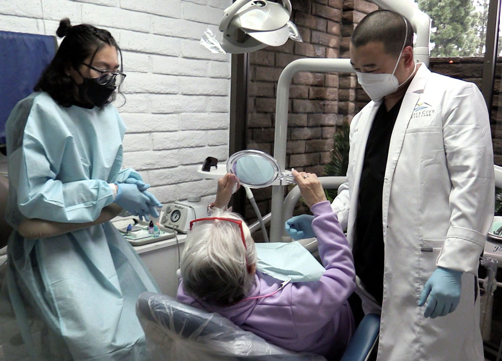 Dr. Kyle working with a patient with assistance looking on.