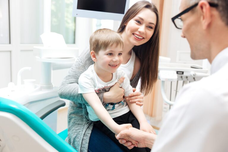 Mother and little boy talking to dentist in dental clinic Child's first visit at the dentist